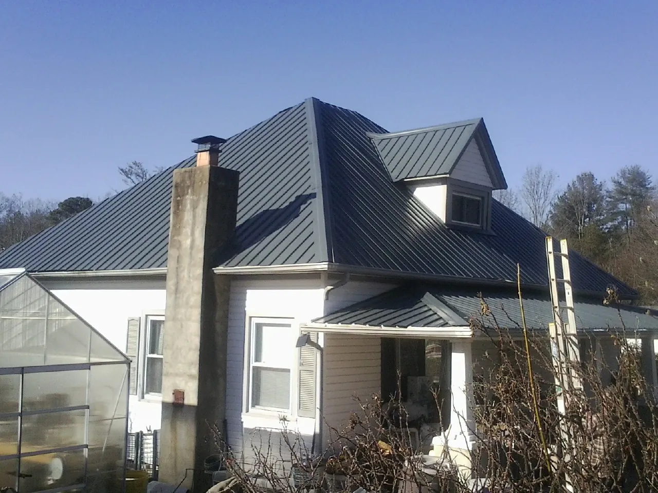 Dark blue standing seam metal roof on a white farmhouse with dormer — Slate & Tile Roof Repair by Roofing Brothers in Achille