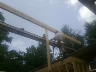 Carpenter setting a ridge beam over a new addition frame — Ice Dam Removal by Roofing Brothers in Achille