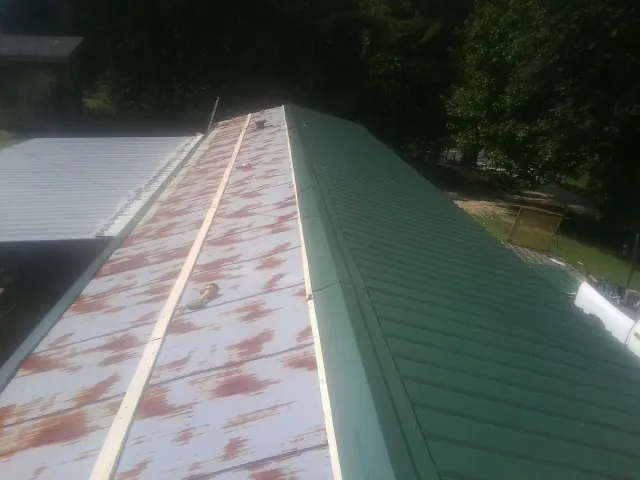 Old rusted panels beside newly installed green metal roofing — Wind Damage Roof Repair by Roofing Brothers in Achille