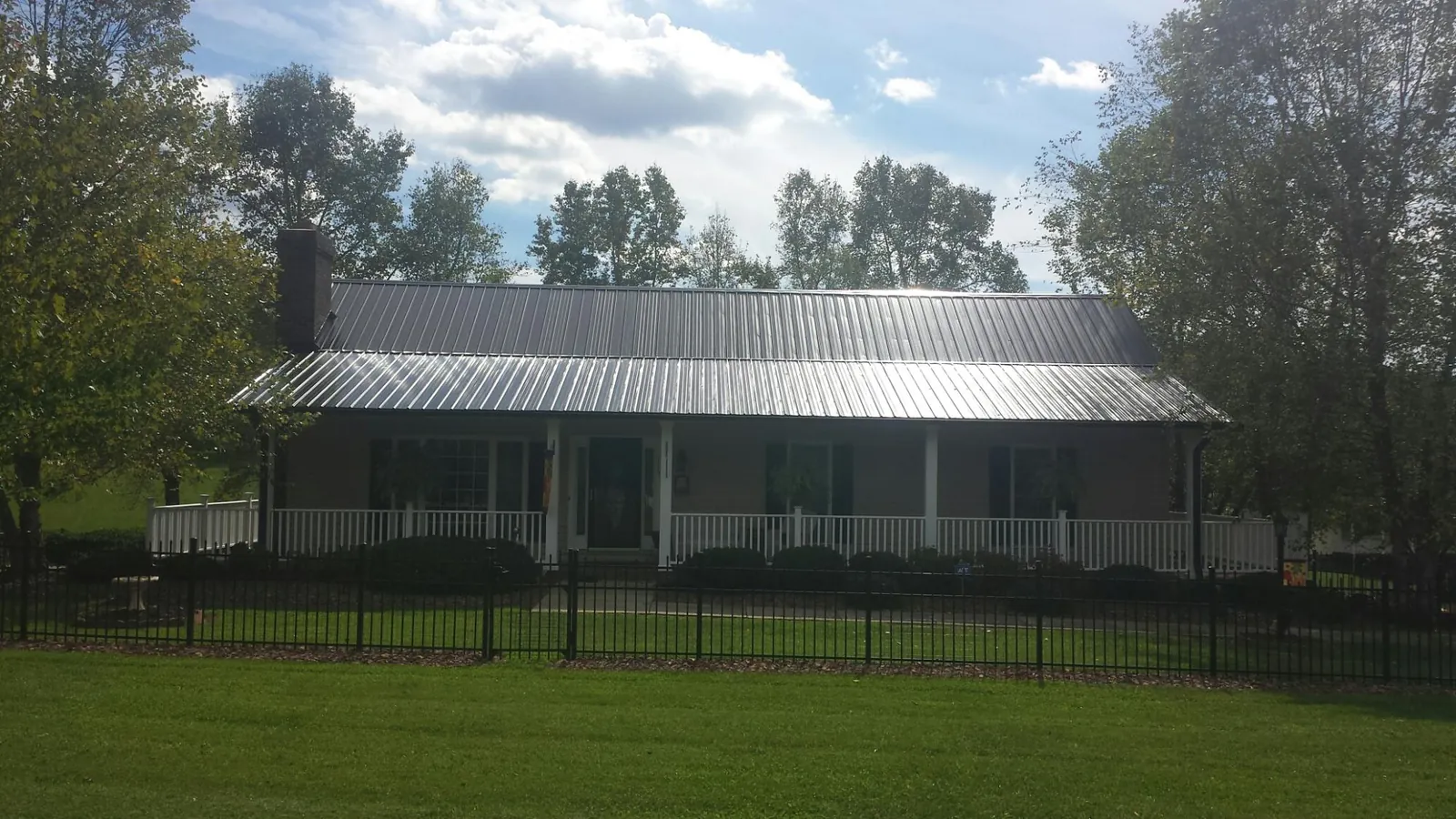 Gray metal roof on a brick ranch with a full width front porch — Gutter Guard Installation work by our crew in Achille